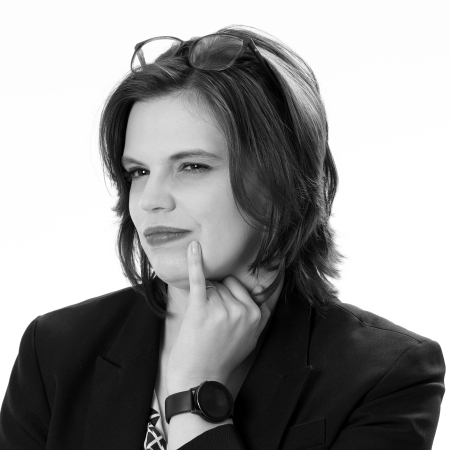 Black-and-white professional headshot of a smiling woman wearing glasses and a dark blazer.